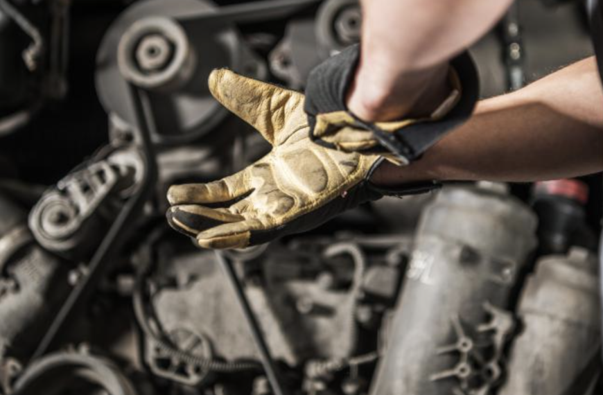 Gloved hands in front of diesel engine