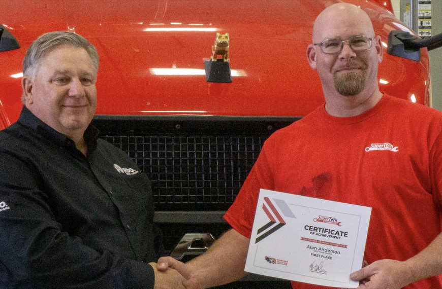 Two men in front of red Mack truck