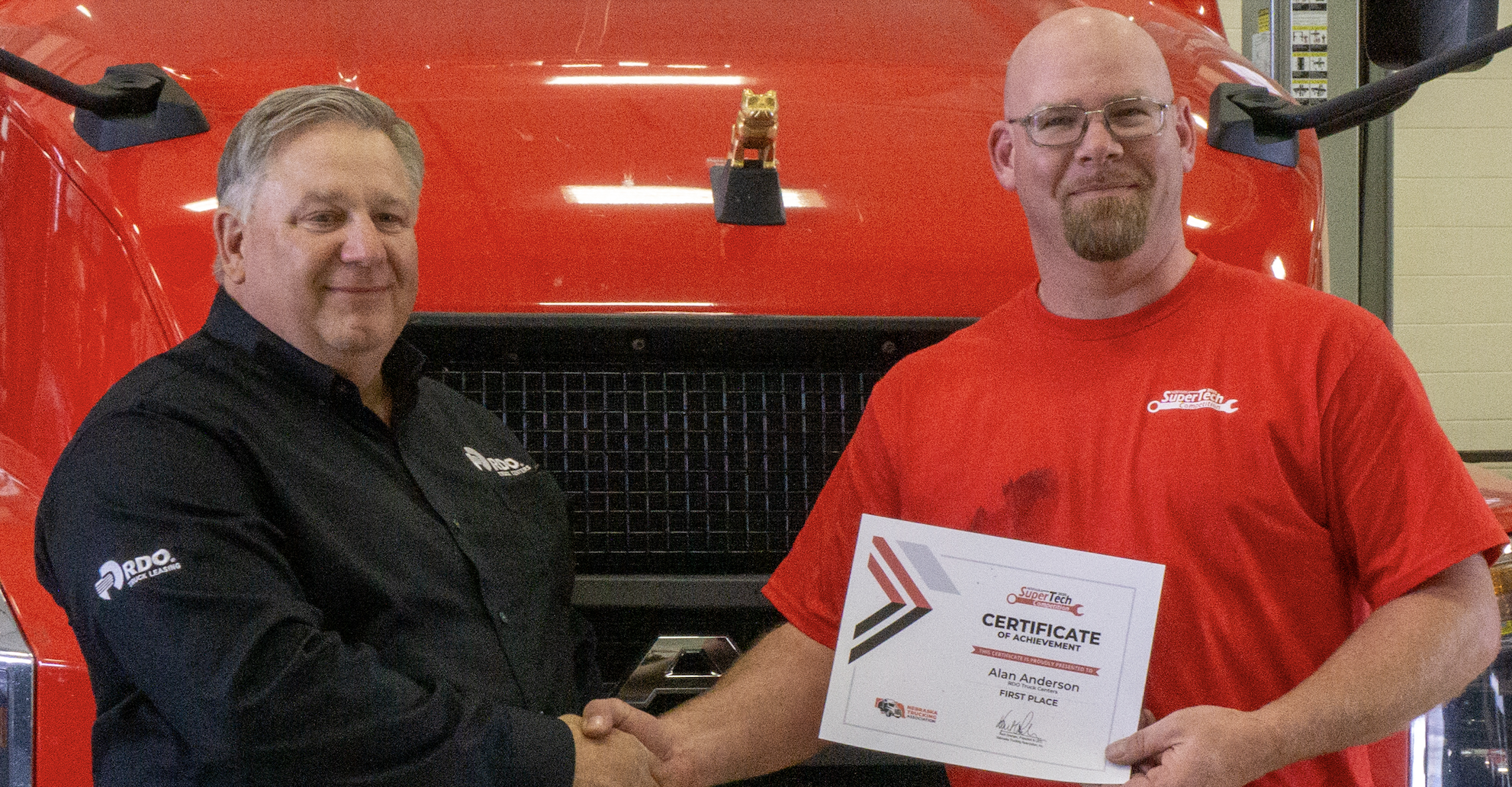 Two men in front of red Mack truck